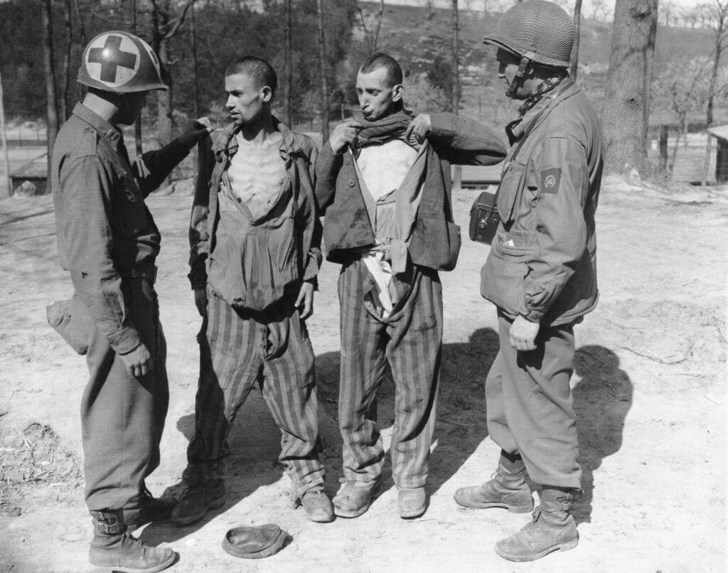 Twee mannen uit een concentratiekamp worden onderzocht door een Rode Kruismedewerker