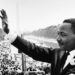 Martin Luther King zwaait naar zijn toehoorders.