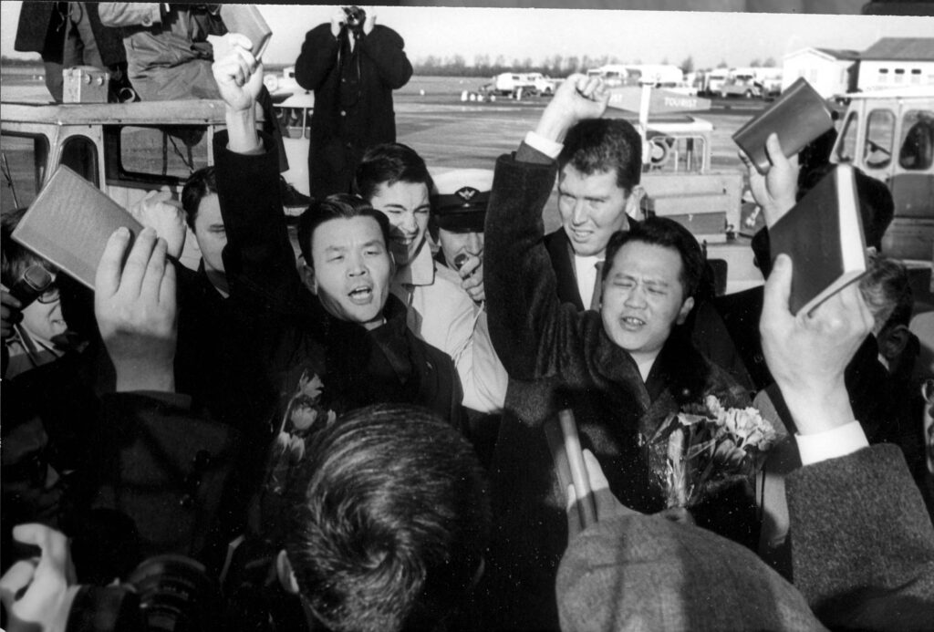 De uitgewezen Chinezen zwaaien op Schiphol met het Rode Boekje van Mao