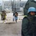 Inwoners van Sarajevo rennen over sniper alley terwijl een VN-soldaat toekijkt.