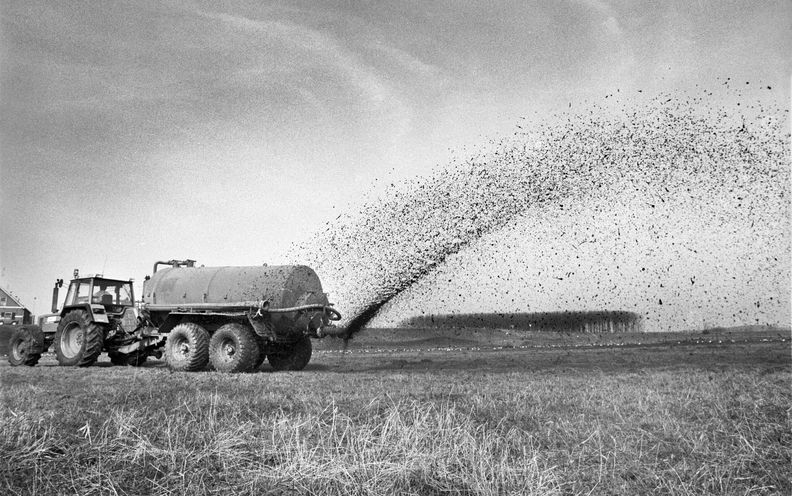 Een boer rijdt vloeibare mest uit over het land
