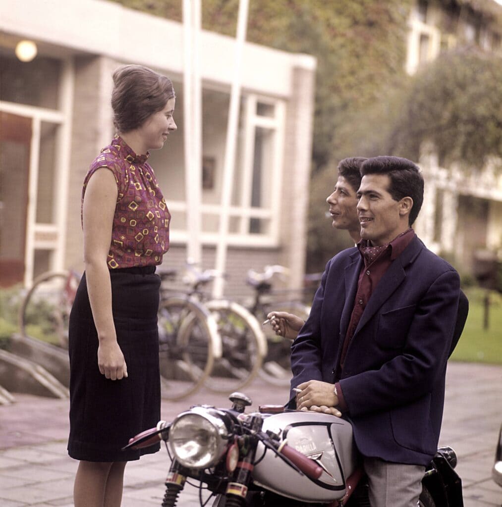 Twee Italiaanse gastarbeiders praten met Nederlandse vrouw