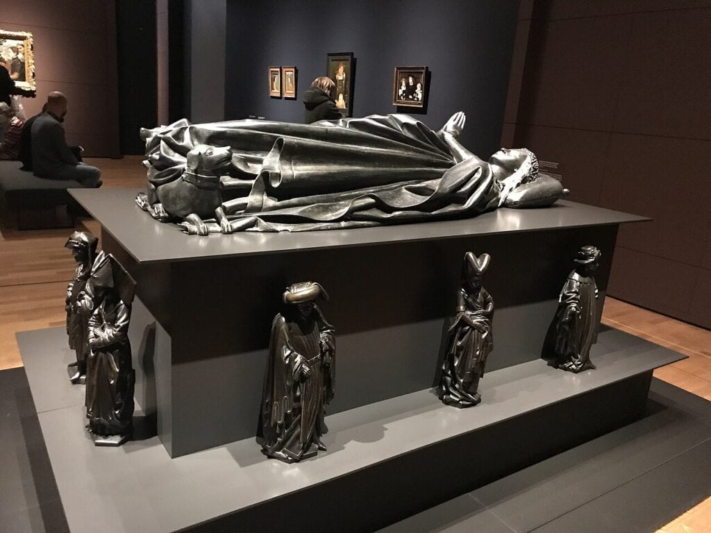 Pleuranten rond een nagemaakte versie van het praalgraf van Isabella in het Rijksmuseum