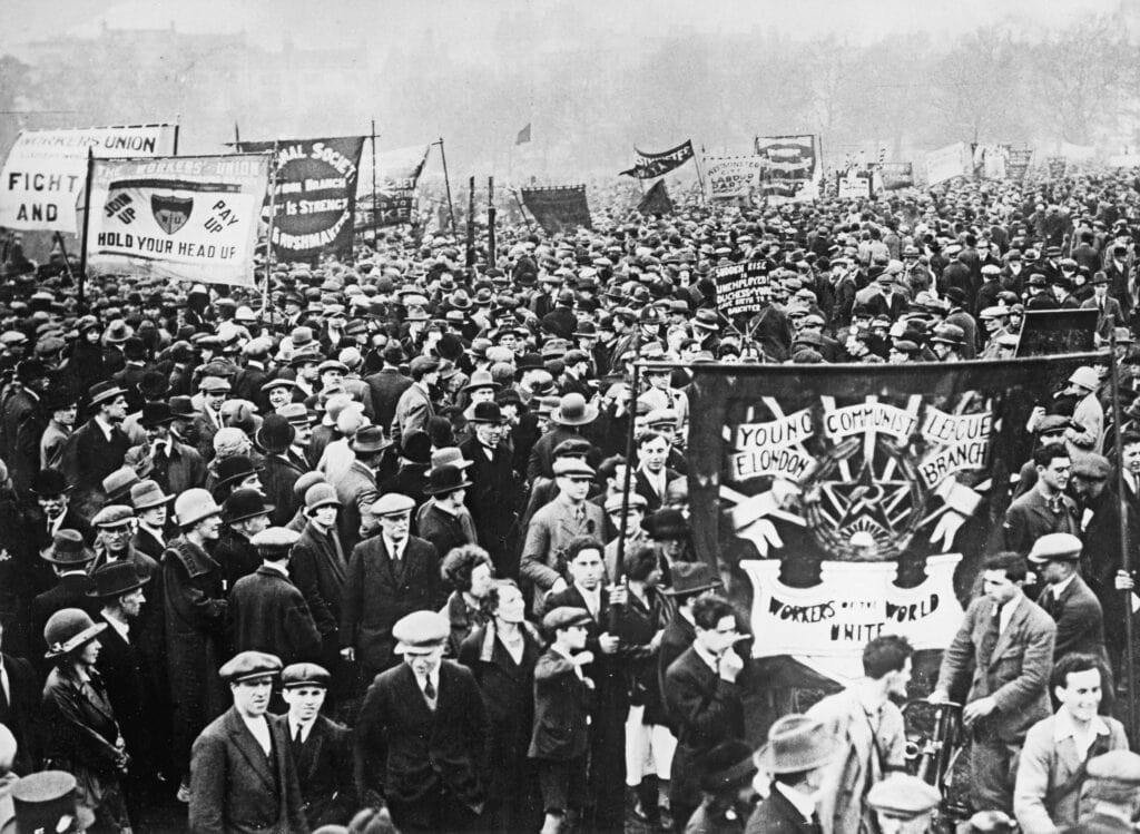 Gouden standaard protestmars met veel mensen en spandoeken.