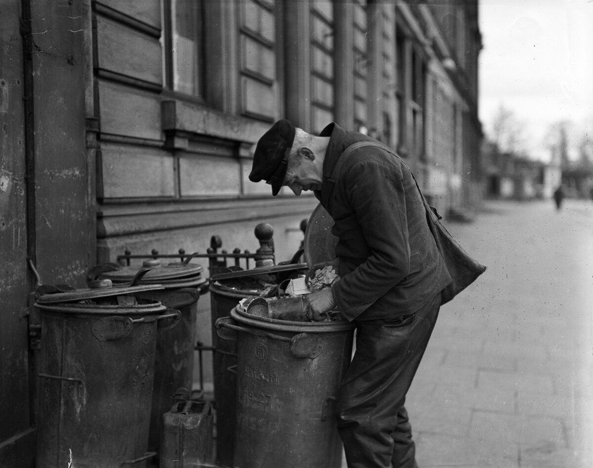 Een Duitse man zoekt in vuilnisbakken naar iets eetbaars. Hamburg, 1946.