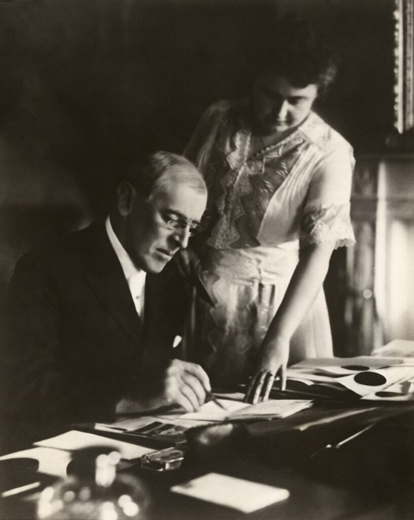 Eerste foto van Woodrow wilson na zijn beroerte in 1920. Zijn vrouw Edith helpt hem een document te ondertekenen.