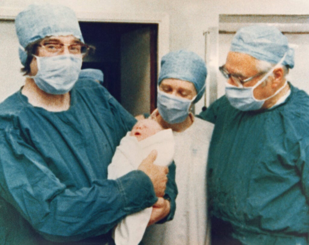 Robert Edwards, Jean Purdy en Patrick Steptoe gaan op de foto met de pasgeboren baby, 25 juli 1978.