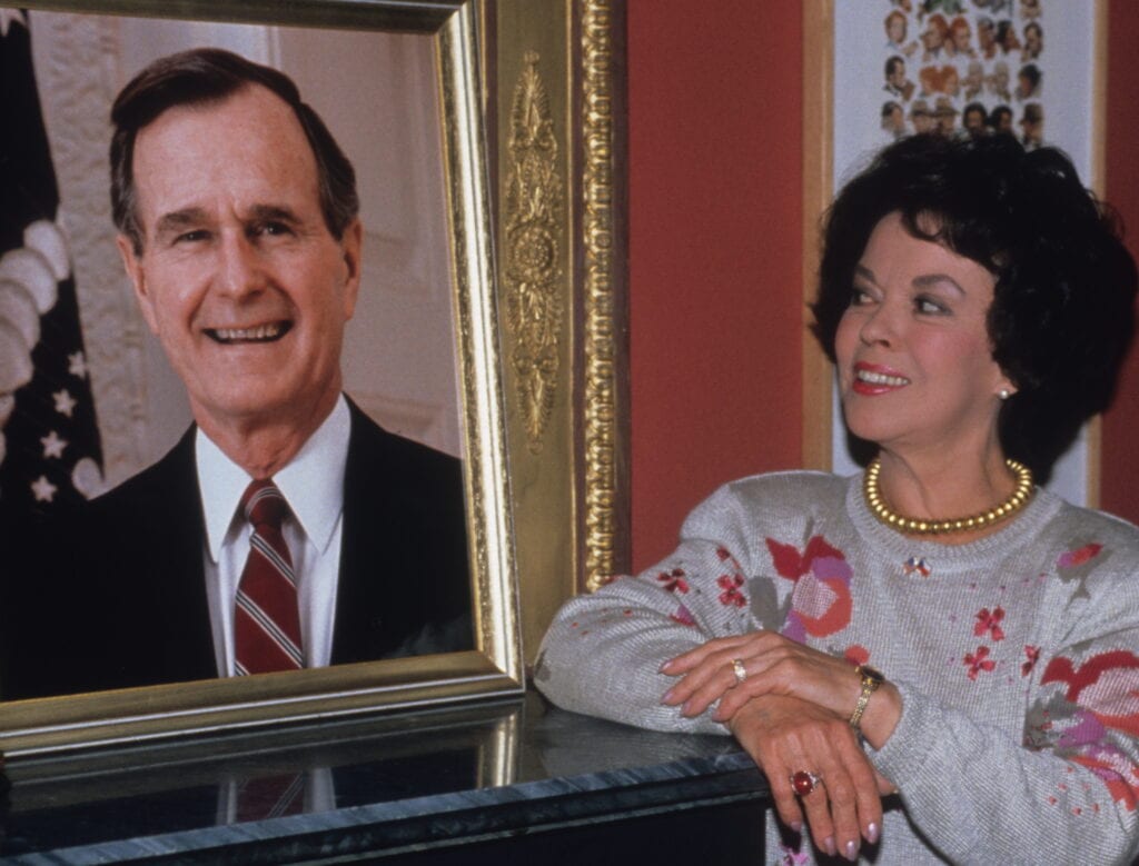 Temple als ambassadeur in Praag naast een portret van George Bush sr, 1989.