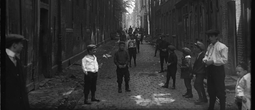Door urbanisatie neemt het aantal kinderen op straat in de steden toe. Uilenburgerstraat in Amsterdam, 1911.